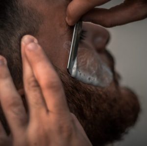 Barbier die een baard bijwerkt met een scheermesje van Feather